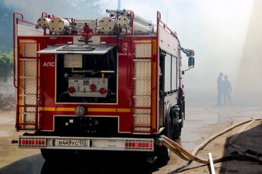 The fire truck works with the smoke zone by fire of a warehouse in Krasnodar clipart