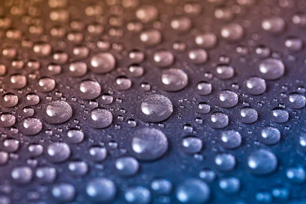 光沢のある粒状の金属表面に水滴 湿った滴と抽象的な青と黄色の背景 — ストック写真