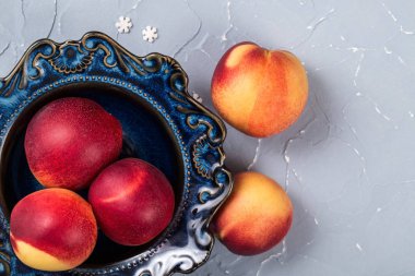Bir vintage mavi plaka olgun nektarinler, masada pürüzsüz şeftali