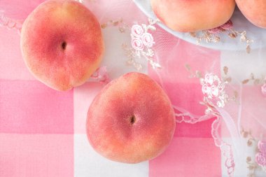 Taze Asya şeftalileri pembe kareli masa örtüsüne yakın plan, yumuşak ve yumuşak meyve