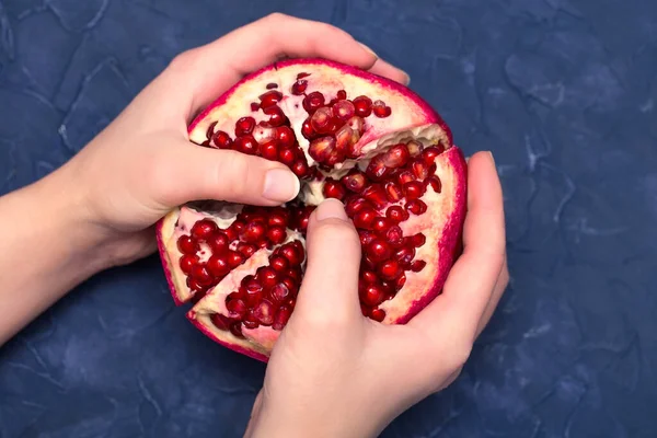 Fresh and ripe pomegranate fruit in women\'s palms. Peeled pomegranate seeds, close-up photo