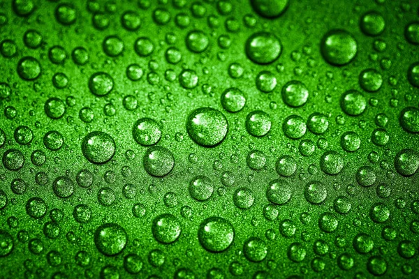 Green water drops on a glitter surface, abstract macro photography