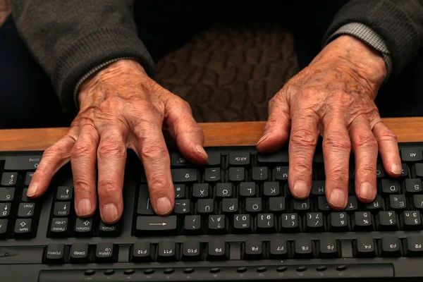 Hands of the old man on the keyboard