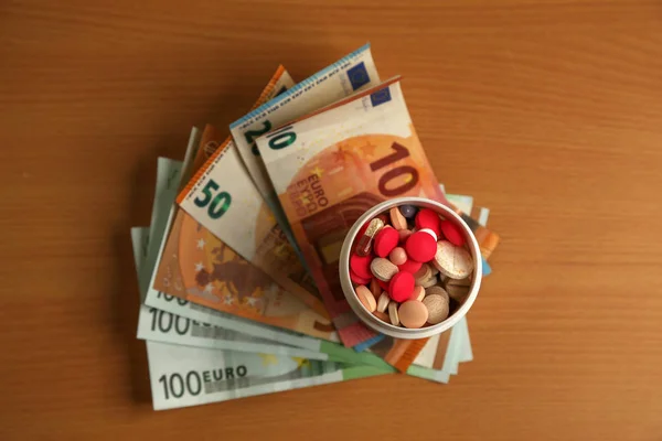 Дорогое лечение лекарствами. Различные таблетки на фоне денег . — стоковое фото