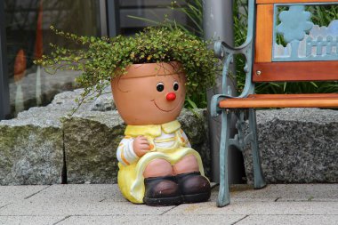 Yeşil bitkiler ile sevimli gülümseyen heykel