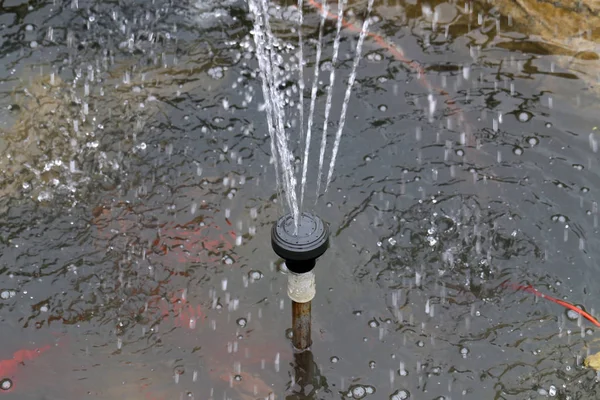 Künstlicher Brunnen in einem kleinen Gartenteich — Stockfoto