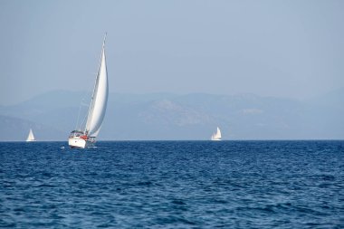Mavi deniz ve gökyüzünün arka planında beyaz yelkenli