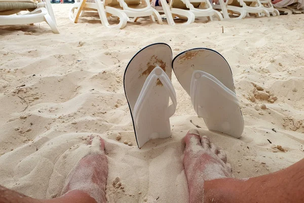 Bare feet and sandals in the sand on the beach