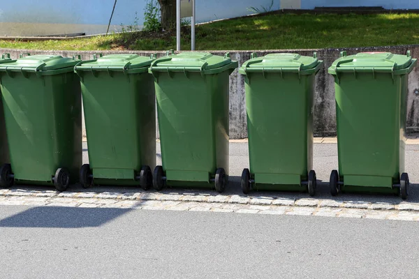 Green garbage cans are on the street