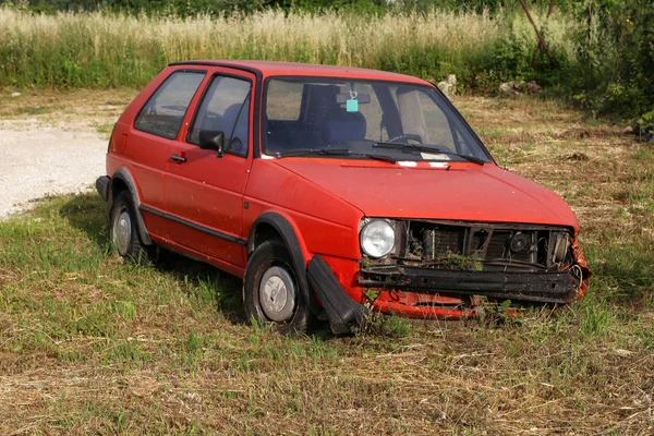 Een oude verlaten auto rust door de weg — Stockfoto