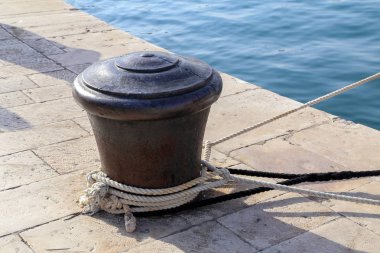 Etrafında bir demirleme halatı olan Bollard.