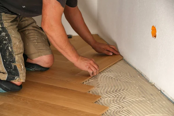 Trabajador que pone suelo de parquet. Trabajador instalación de pisos laminados de madera — Foto de Stock