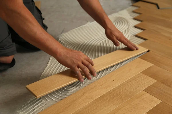 Trabajador que pone suelo de parquet. Trabajador instalación de pisos laminados de madera — Foto de Stock