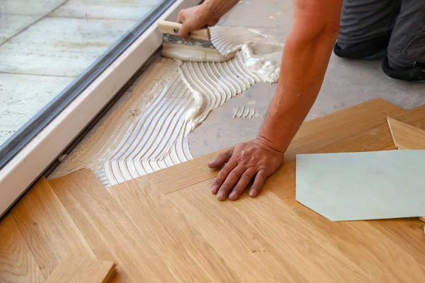 Trabajador que pone suelo de parquet. Trabajador instalación de pisos laminados de madera — Foto de Stock