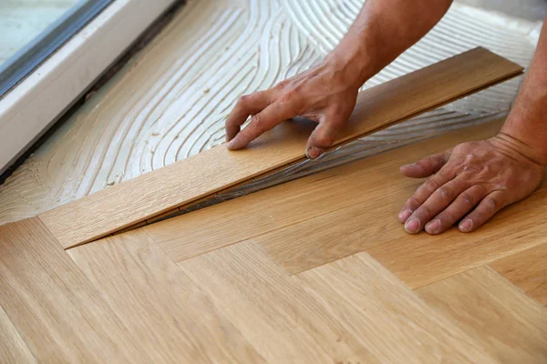 Trabalhador que estabelece piso em parquet. Trabalhador de instalação de piso laminado de madeira — Fotografia de Stock