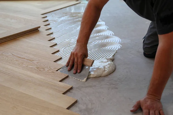 Trabajador que pone suelo de parquet. Trabajador instalación de pisos laminados de madera —  Fotos de Stock