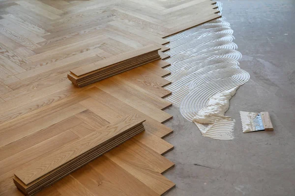 Trabajador que pone suelo de parquet. Trabajador instalación de pisos laminados de madera — Foto de Stock