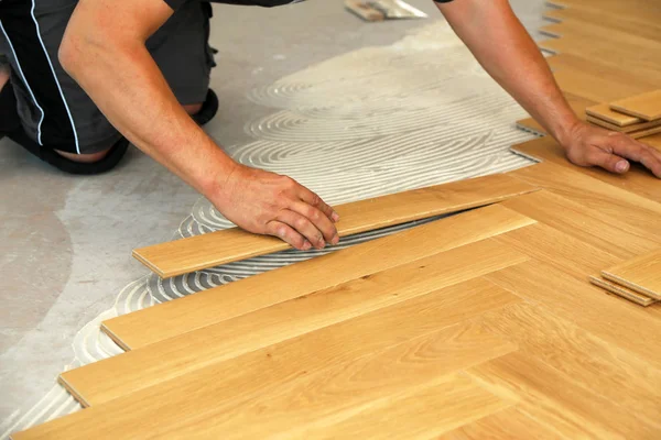 Trabajador que pone suelo de parquet. Trabajador instalación de pisos laminados de madera —  Fotos de Stock