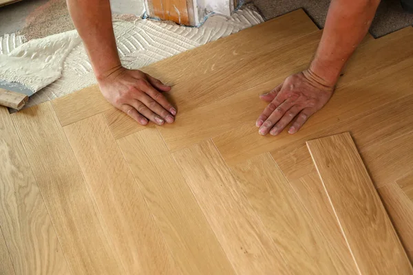 Trabajador que pone suelo de parquet. Trabajador instalación de pisos laminados de madera — Foto de Stock