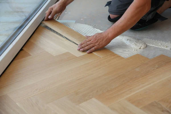 Trabajador que pone suelo de parquet. Trabajador instalación de pisos laminados de madera — Foto de Stock