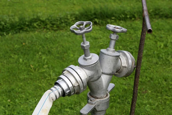 Silver fire hydrant with a hose closeup — Stock Photo, Image