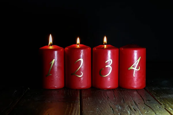 3. Advent. Rote Adventskerzen stehen auf einem Holzboden Stockfoto