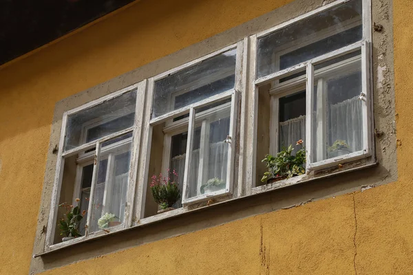 Vieilles fenêtres avec des fleurs sur le rebord de la fenêtre — Photo