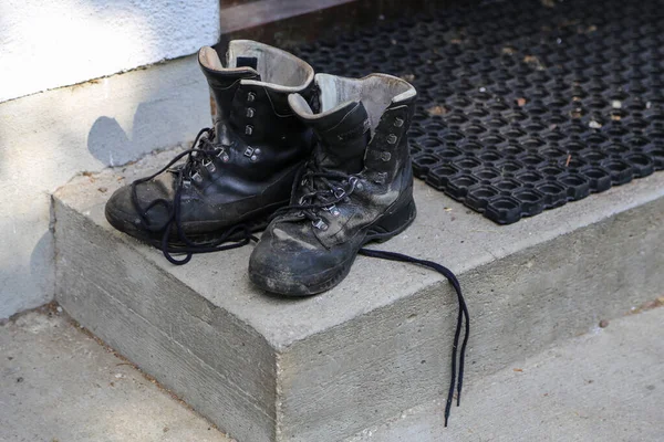 Грязная обувь стоит на крыльце дома — стоковое фото
