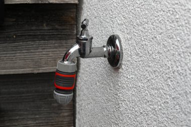 Yazın evin duvarında bahçeyi sulamak için musluk.