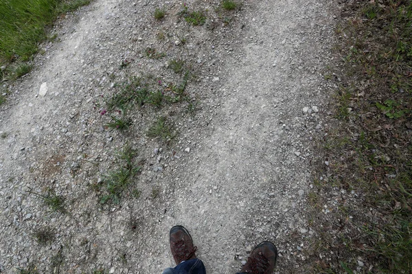 Feet in brown shoes on the road of gravel