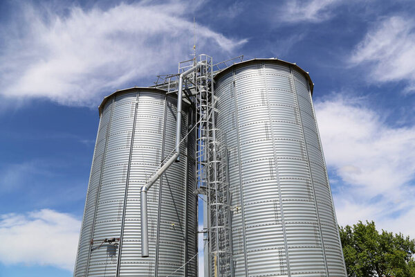 Metallic silos in white over the sky.