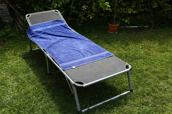 A folding bed is in the garden on the green grass.
