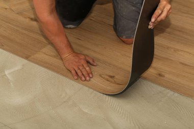 The worker installing new vinyl tile floor. clipart
