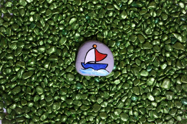 Funny painted stone with the image of a sailing boat on the waves