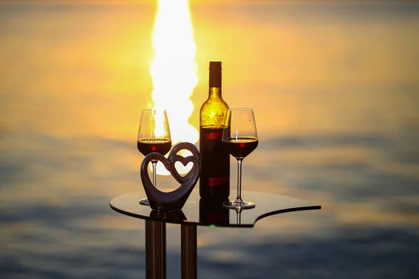 Composition of glasses and bottles with red wine at sunset