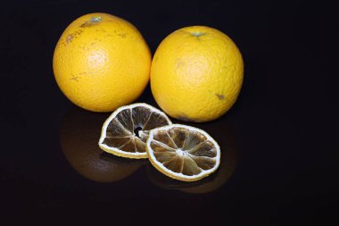 Siyah arka planda taze portakallar ve kurutulmuş dilimler..