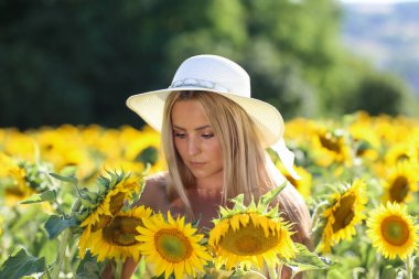 Genç bir bayan ayçiçeği tarlasında duruyor..