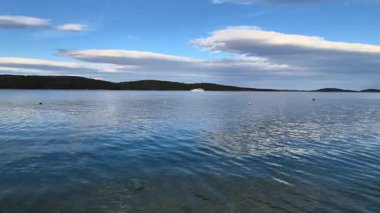 Yaz tatili konsepti için arka plan. Kumsalın ve denizin doğası, güneş ışığıyla yaz, kumlu sahil, köpüklü deniz suyu mavi gökyüzü ile çelişiyor.