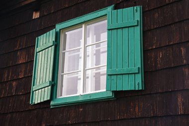 Ahşap bir evin camlarında yeşil panjurlar.