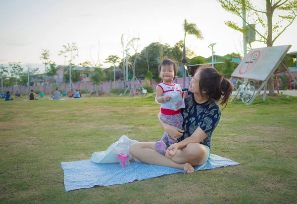 Parkta piknik sırasında oturan anne ve çocuk kız