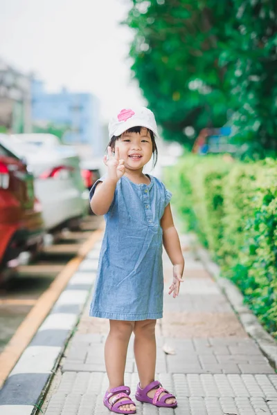 小さな女の子を着用する公園で白い帽子立っていると幸せ 旅行する準備ができての笑みを浮かべて — ストック写真
