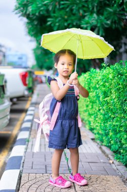 küçük kız şemsiye ve okula geri gün yağmur içinde hazır Park'ta yürüyordunuz sırt çantası