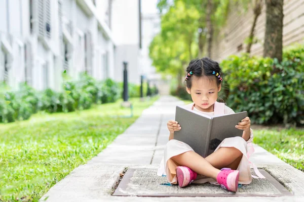 küçük kız okula hazır parkta oturan sırt çantası ile bir kitap okuma