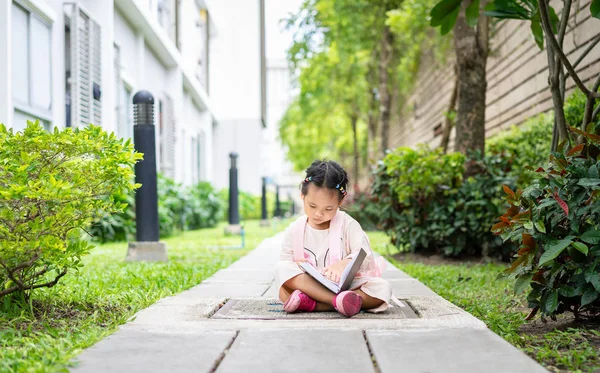 Маленькая Девочка Читает Книгу Рюкзаком Сидя Парке Готовый Вернуться Школу Лицензионные Стоковые Фото
