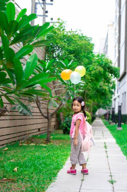 sırt çantası ve parkta yürüyüş balon ile küçük kız