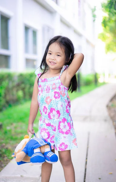 Portret szczęśliwej azjatyckiej dziewczynki z lalką stojącą na footpa — Zdjęcie stockowe