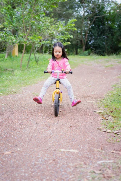 Маленькая девочка учится кататься на велосипеде на склоне в парке Стоковое Изображение