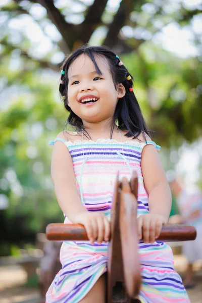 Asian trochę dziewczyna mający zabawa na huśtawce w plac zabaw dla dzieci — Zdjęcie stockowe