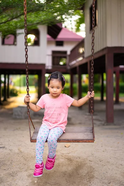 Mała dziewczynka siedzi na huśtawce w parku — Zdjęcie stockowe