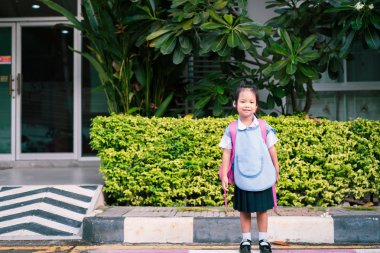 Tay okul üniforması içinde ayakta mutlu küçük kız portresi